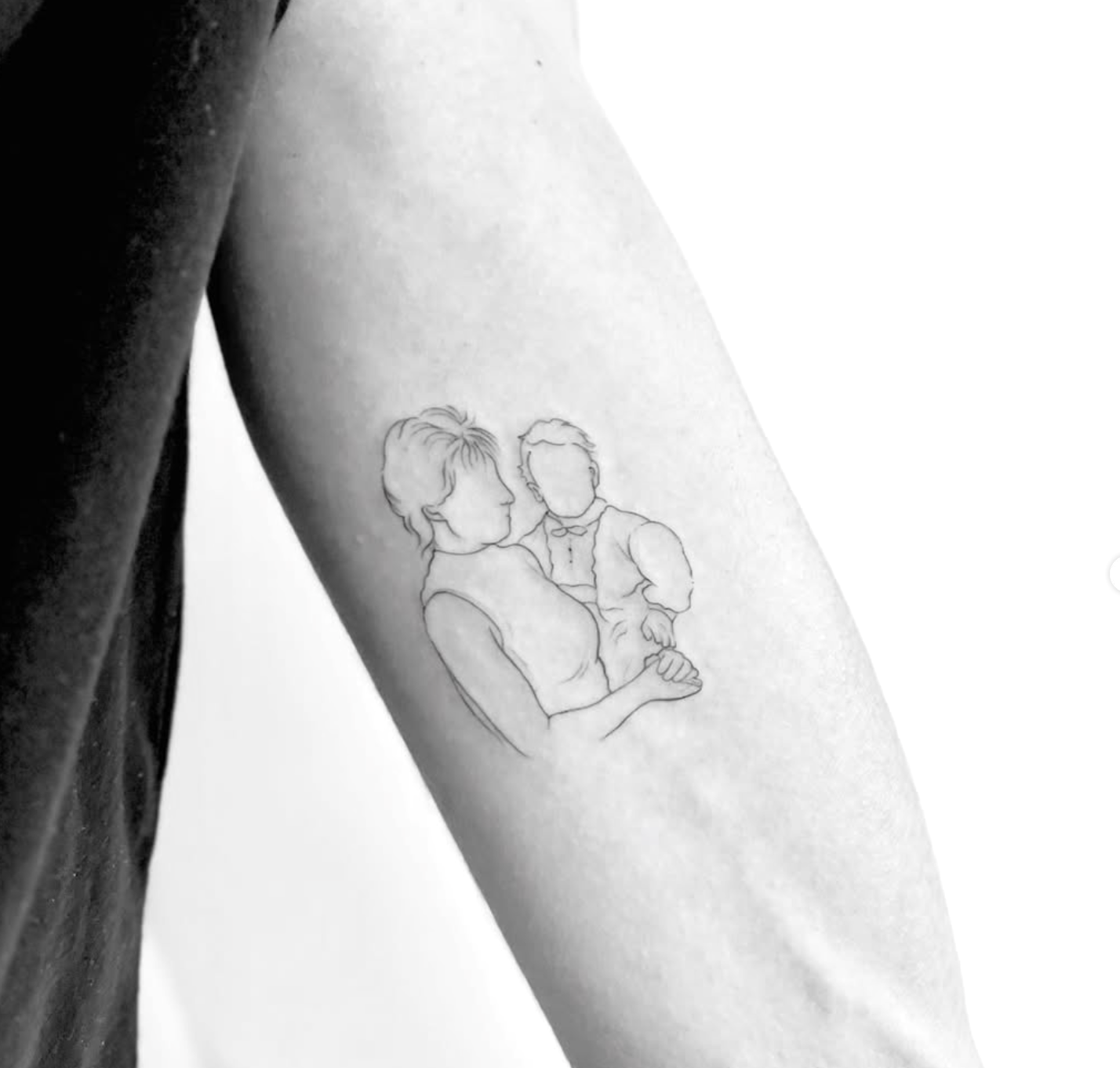Tatuagem fine line com o contorno de uma mãe a segurar o filho ao colo