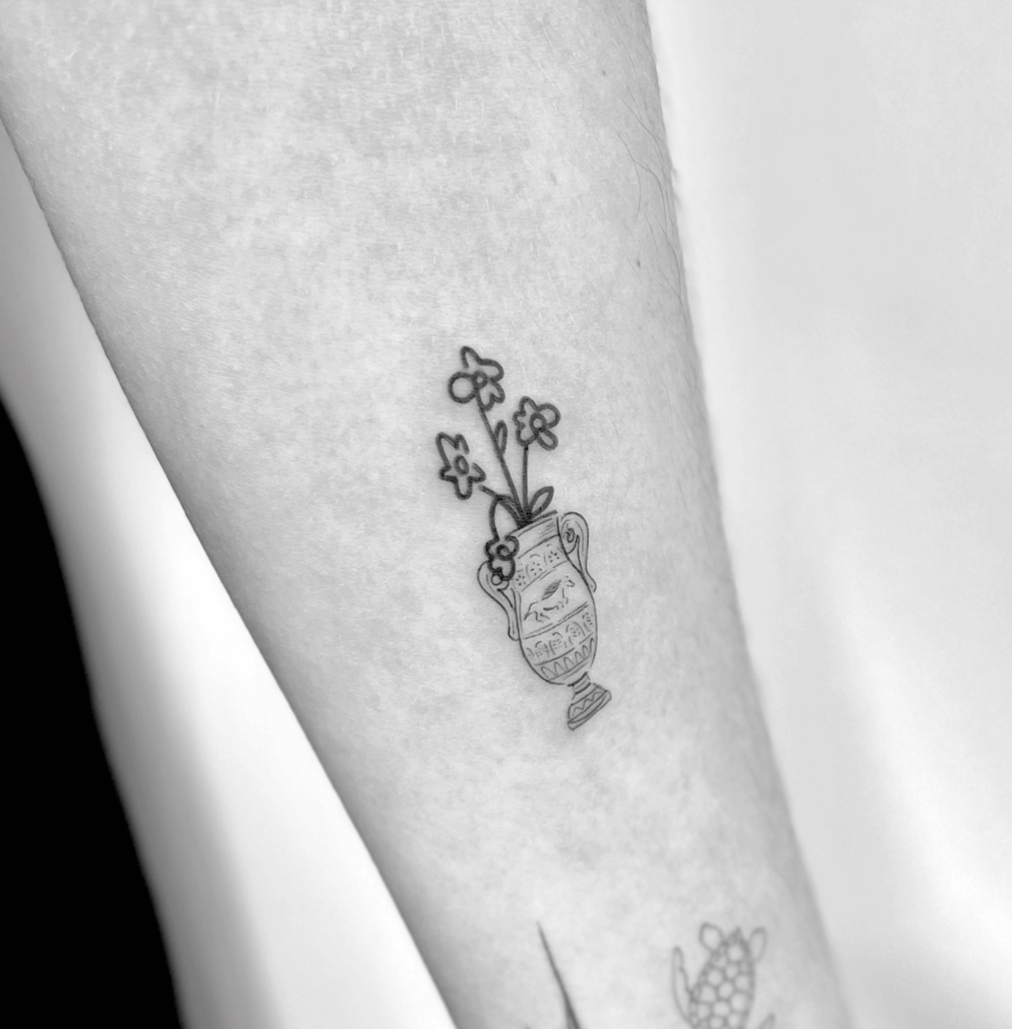 Tatuagem fine line de ânfora grega com flores