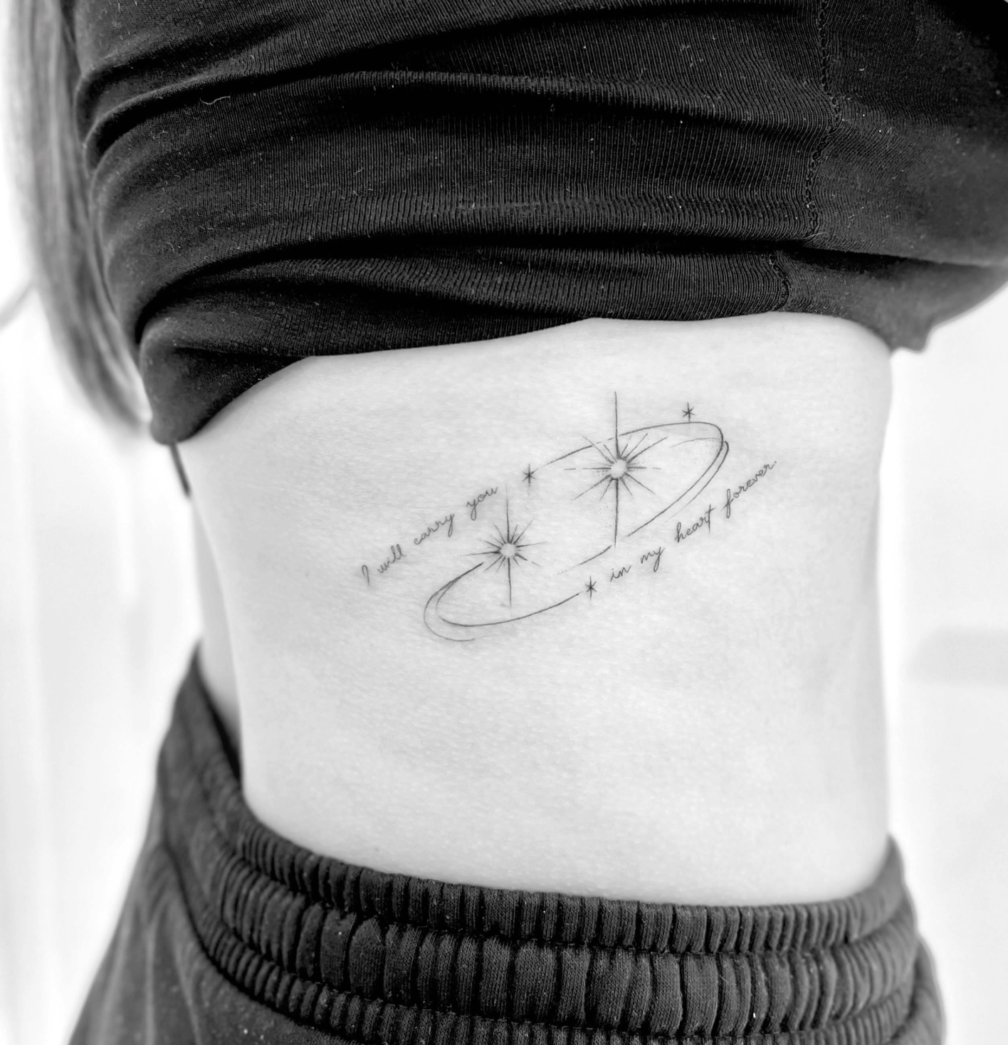 Tatuagem fine line de planeta e estrelas com a frase I will carry you in my heart forever