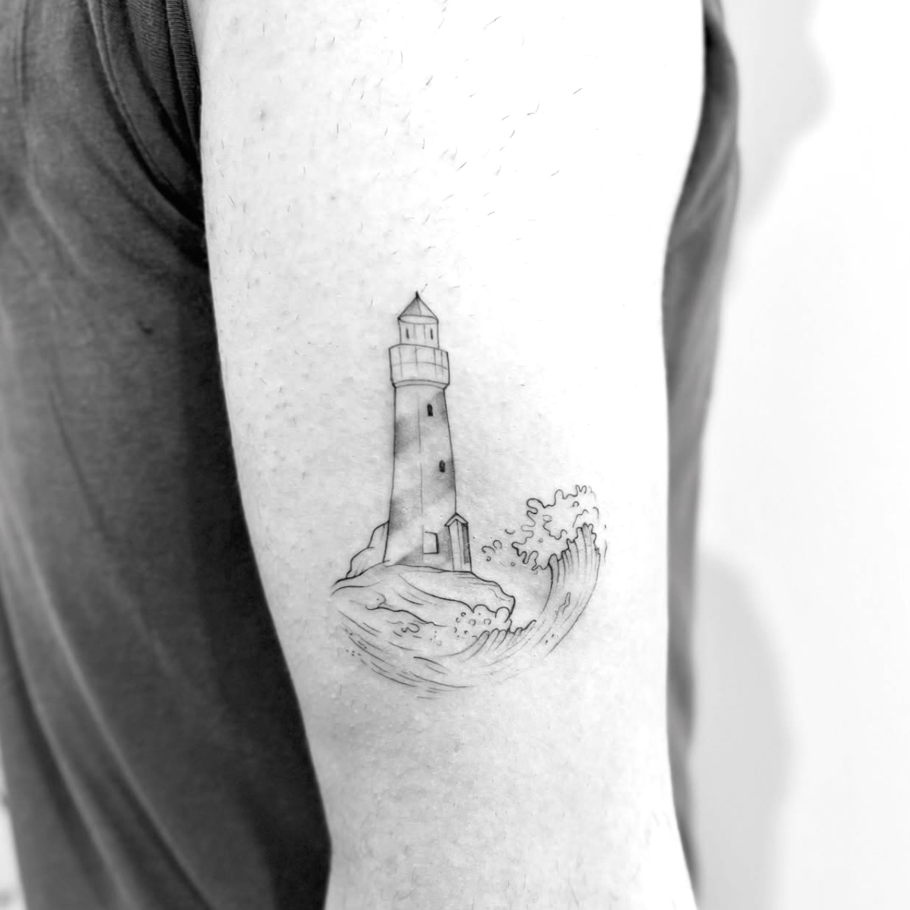 Tatuagem fine line de um farol com ondas