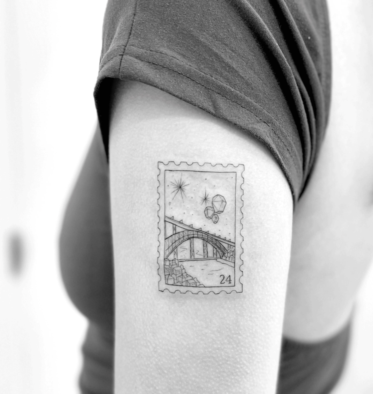 Tatuagem fine line em forma de selo postal com a ponte do Porto